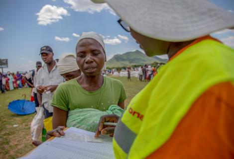 ActionAid staff member manages a food distribution in Zimbabwe. Women are queuing for food support