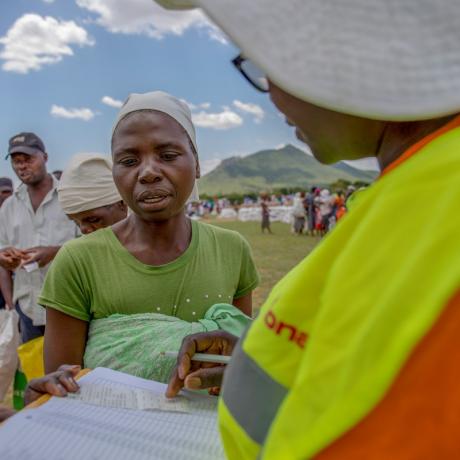 ActionAid staff member manages a food distribution in Zimbabwe. Women are queuing for food support