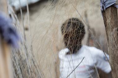 An anonymous woman is seen through the net of a fishing net.